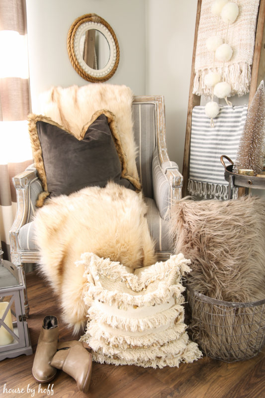 Faux fur throws, neutral large pillows all in living room on armchair.