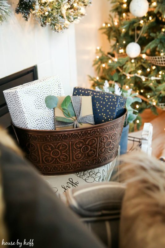 Wrapped presents in a metal bucket beside the Christmas tree.