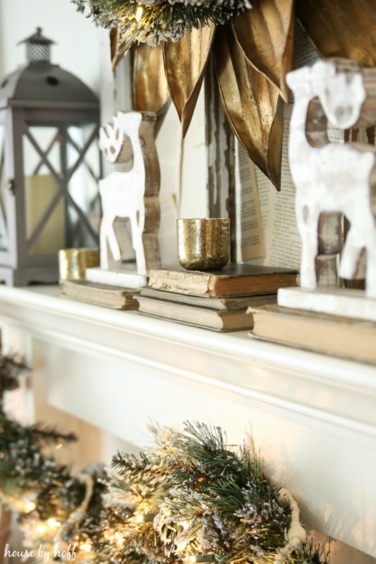 Two wooden reindeer on the mantel a top of antique books.