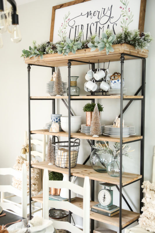 Shelving unit with garland and trees on it.