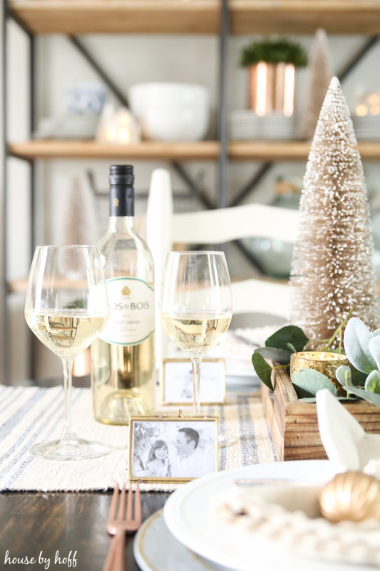 Photo name cards on the table with a bottle of wine wine and two wine glasses.