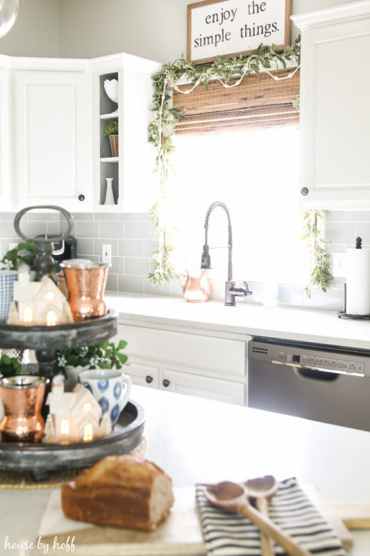 Enjoy the simple things picture above the sink, a loaf of bread on the counter beside the metallic tray.