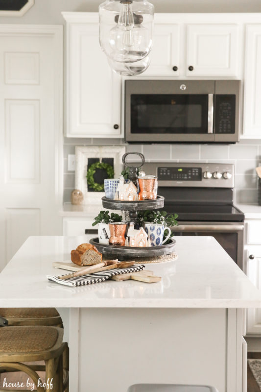 A white island, wicker chairs and pendant lights over the kitchen island.