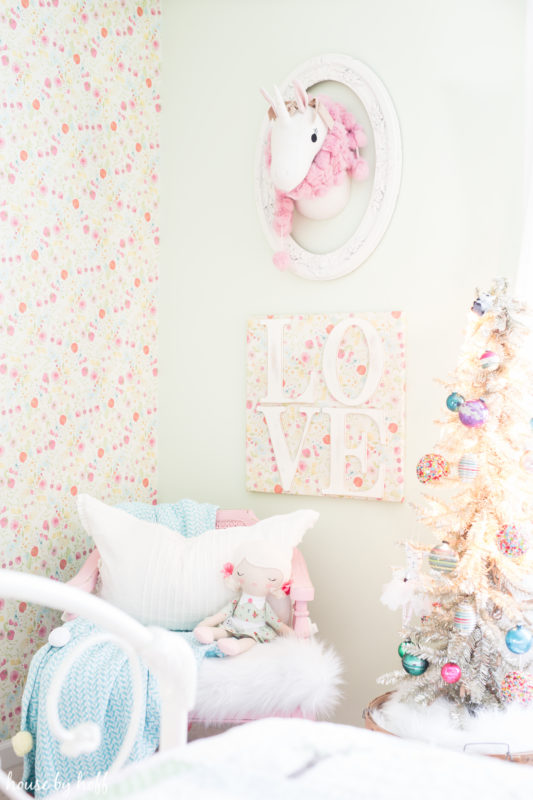 A small unicorn is on the wall with a decoration around it.