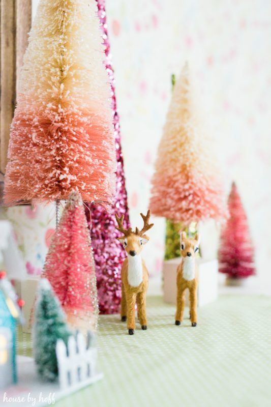 Up close picture of the little reindeer figurines beside the trees.