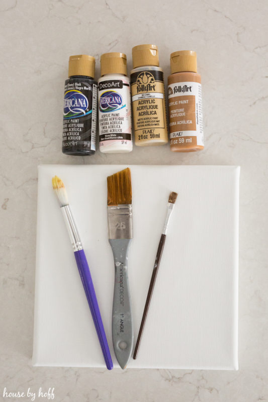 Paint, paint brushes and a white plate on the counter.