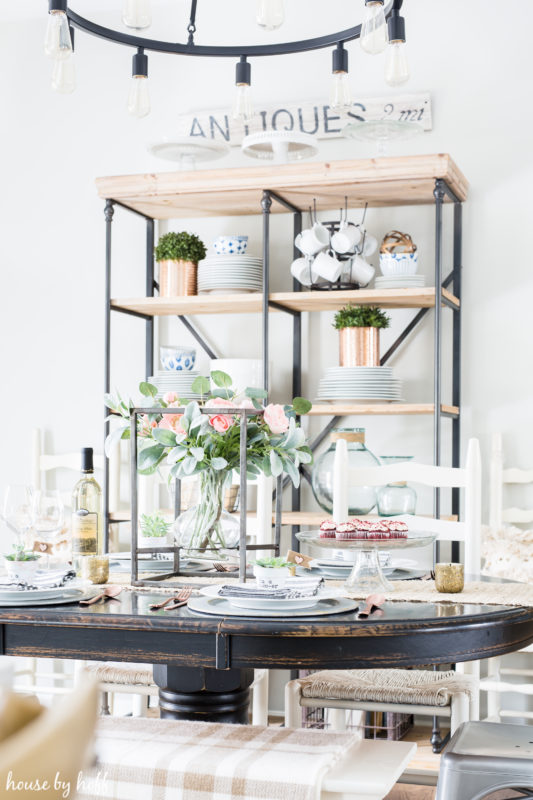 A wooden table with a floral arrangement in the middle of the table.