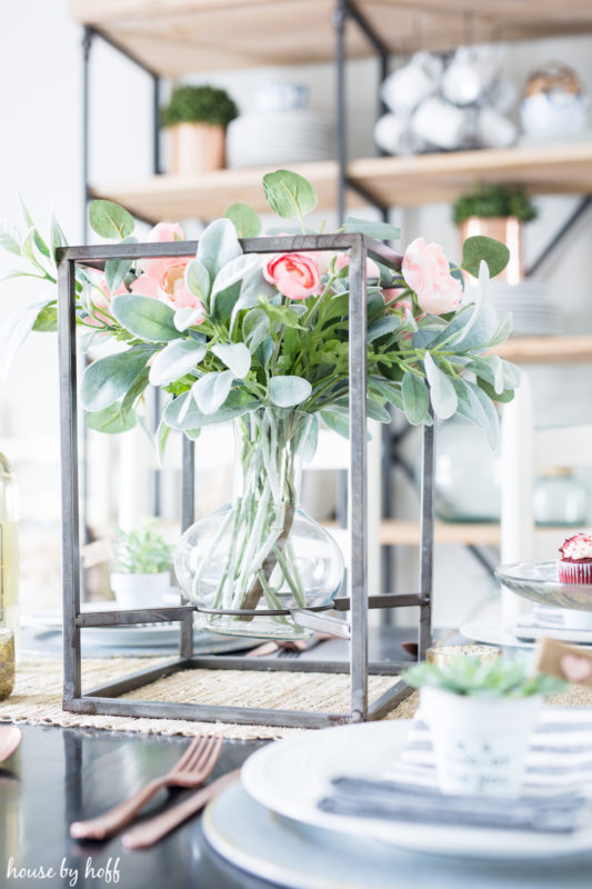 Soft pink roses in a rustic metal box holding the clear vase on the table.