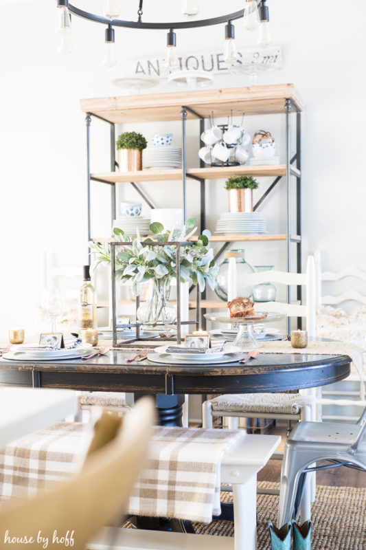 Wooden table in dining room with open shelving behind it.