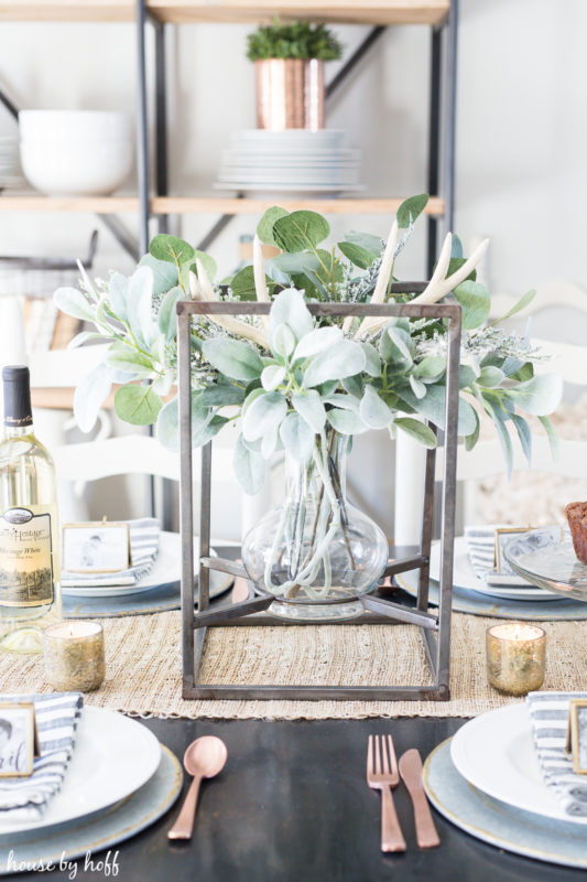 Clear glass vase with winter greenery in it on the table.