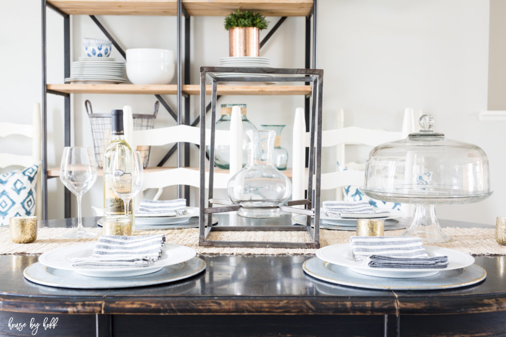 White plate setting on table with a cake stand on the table as well.