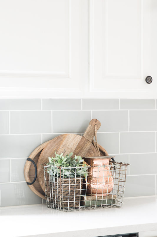 Fake plant and cutting board on kitchen counter.