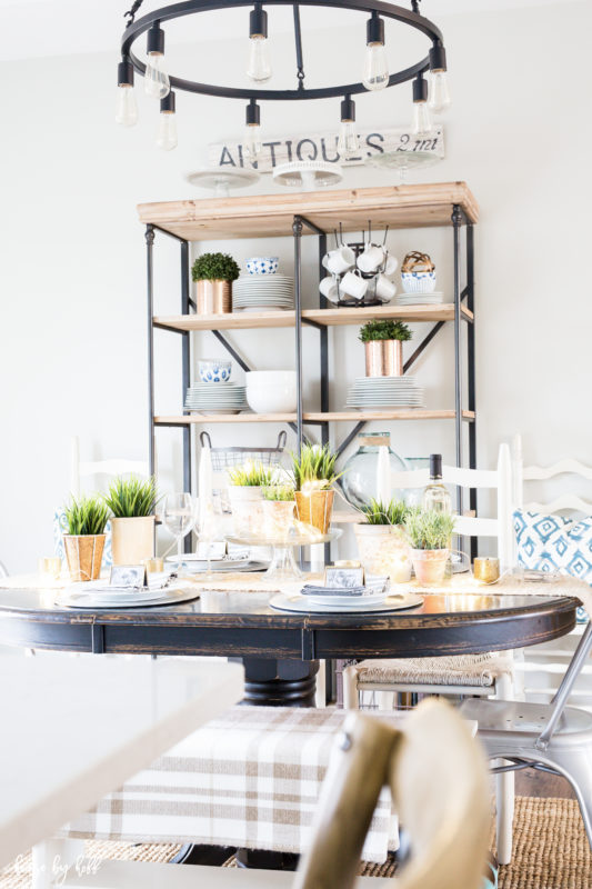 A dining room table with open shelving behind the table.