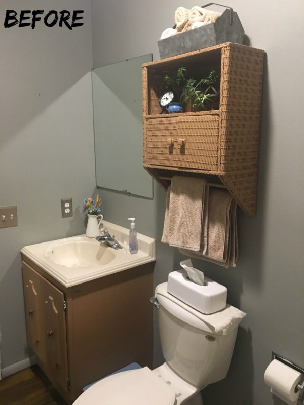 Wooden cabinet, white toilet and wicker medicine cabinet in bathroom.