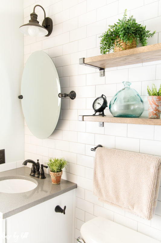 Small round mirror on the wall in bathroom underneath the light fixture.