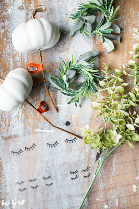 The pumpkins, leaves and eyelashes on a table.