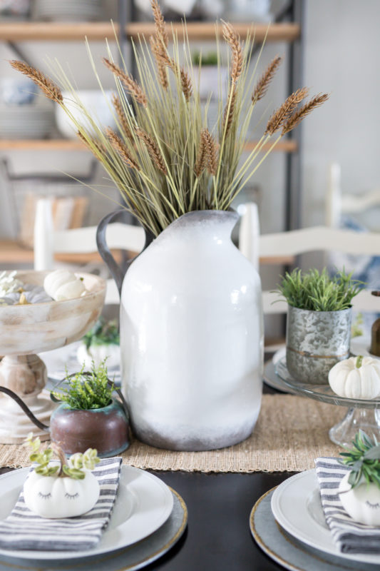 White vase filled with wheat on the table.