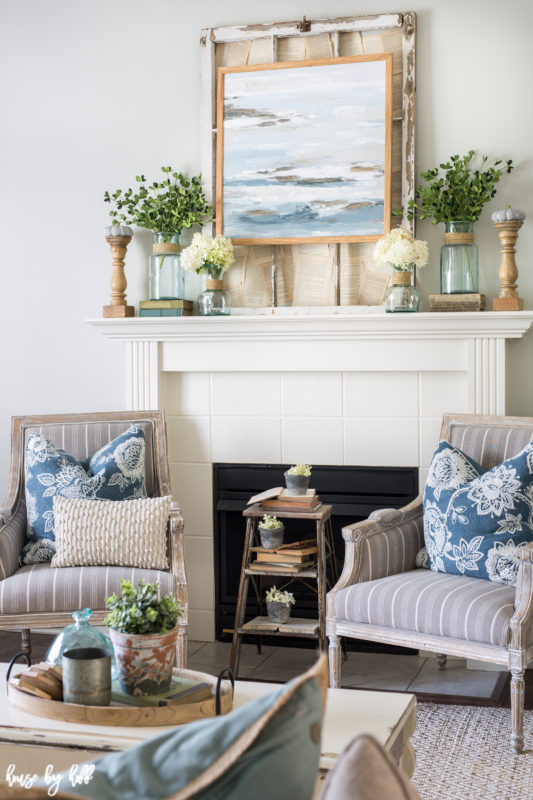 White mantel with armchairs in front of it and a side table.