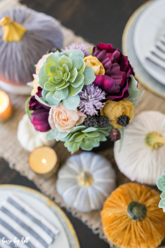 Velvet pumpkins and candles on table.