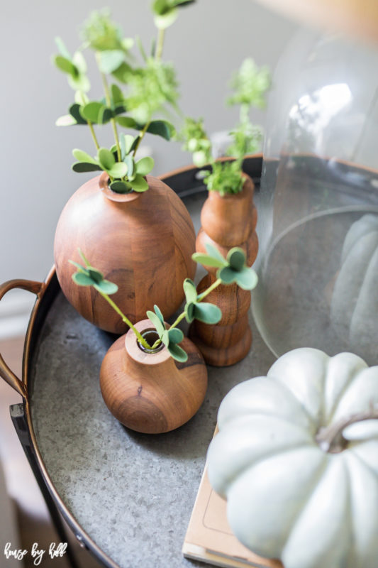 Wooden little vases with green plants in them on a serving tray.