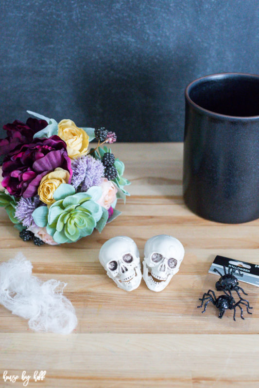 Skull heads, flowers, mesh and a black vase on the counter.