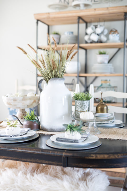 Wooden table with white vase and sprigs of wheat.