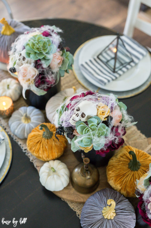 Large skull heads in a floral and succulent arrangement on the table.