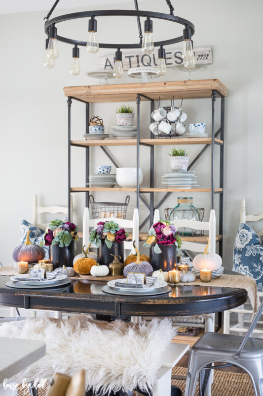 Decorated dining table for fall with shelving unit in the background.