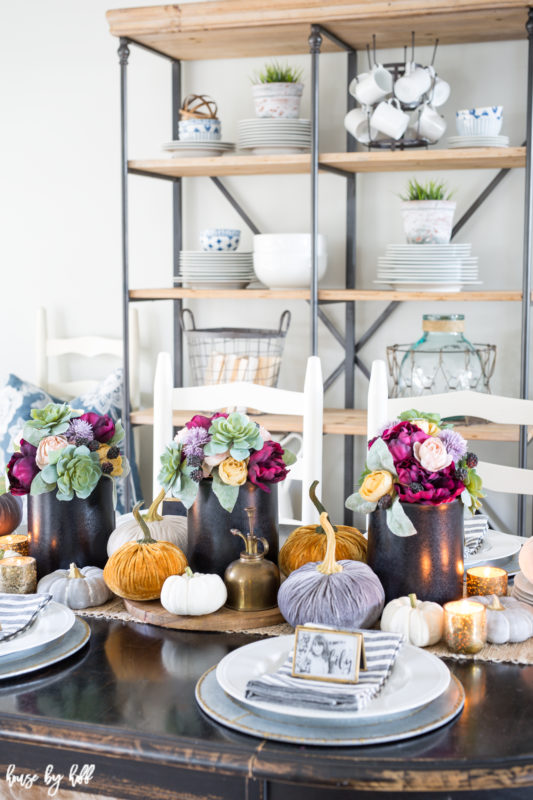 Wooden table with flowers and pumpkins on it.