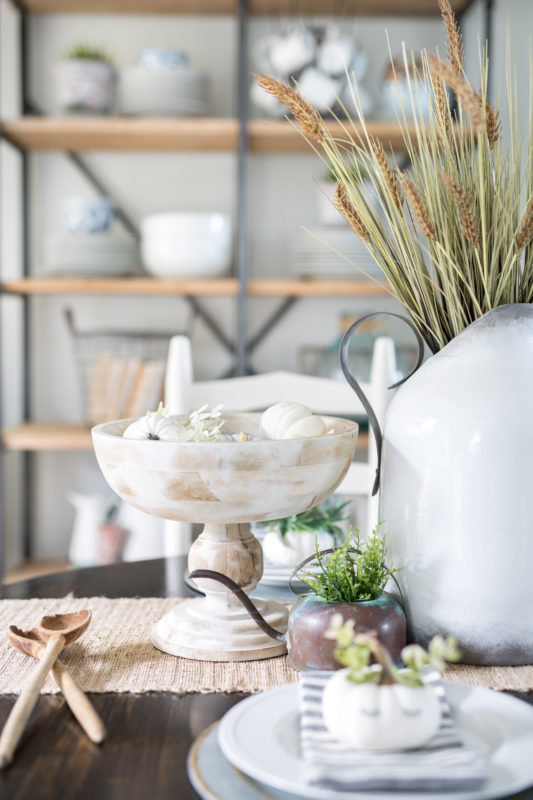 Pedestal white bowl and wooden spoons on the table.