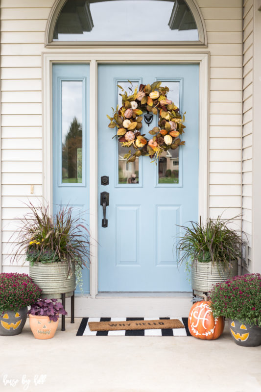 Blue front door of a house with a Fall wreath on it.