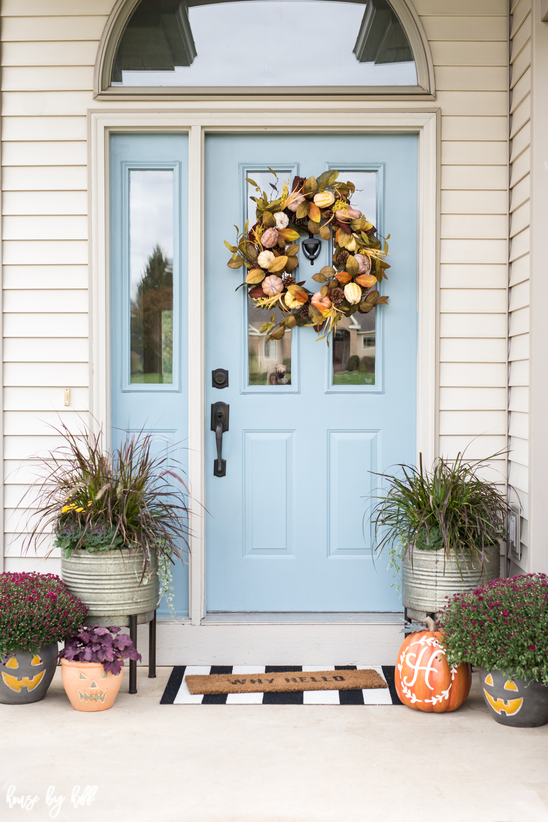 Blue front door of a house with a Fall wreath on it. 