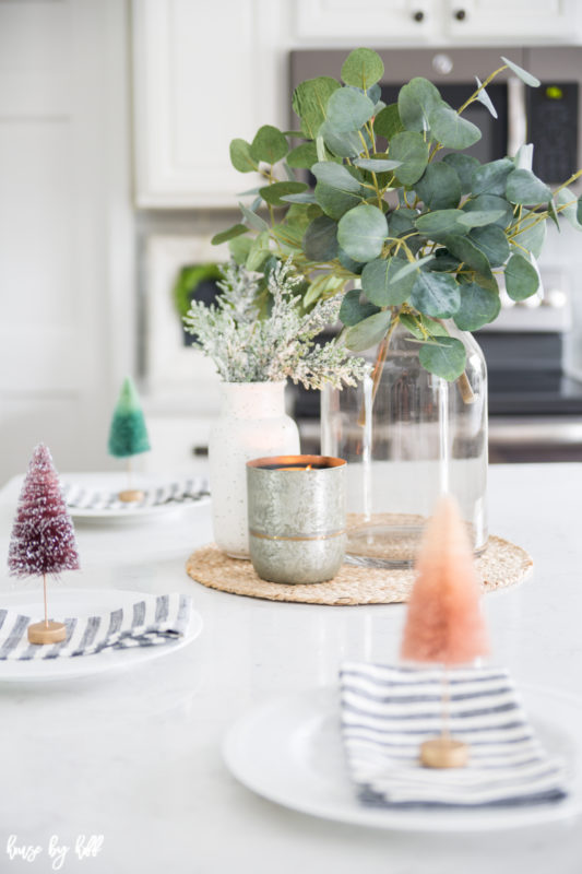 Eucalyptus leaves in a clear glass jar is in the middle of the kitchen island.