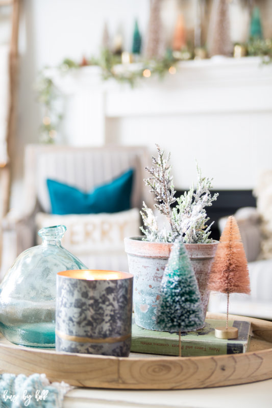 Candles, potted plant, green and orange trees on a tray.