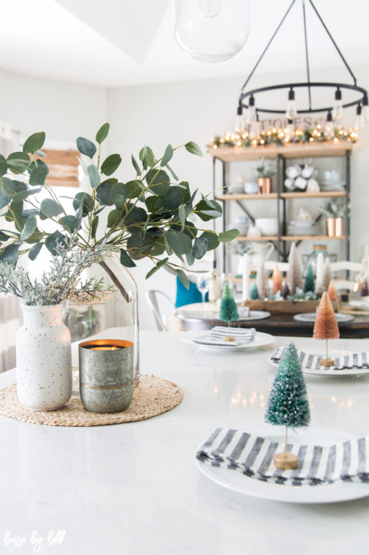 Mini trees, white plates and striped napkins on the white island by the dining room.