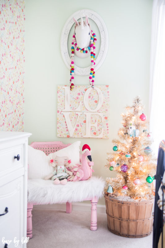 Multicolored beads hanging around the unicorn head, and a pink armchair in the corner of the room with dolls on it.