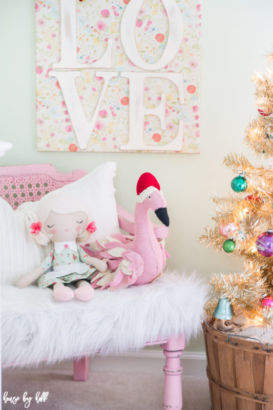 A love picture on the wall, with a little doll and flamingo on a pink chair under the picture.