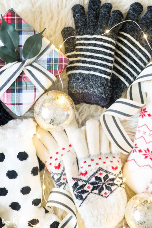 A wrapped present with green leaves, Christmas ornaments, gloves and socks on the faux fur.