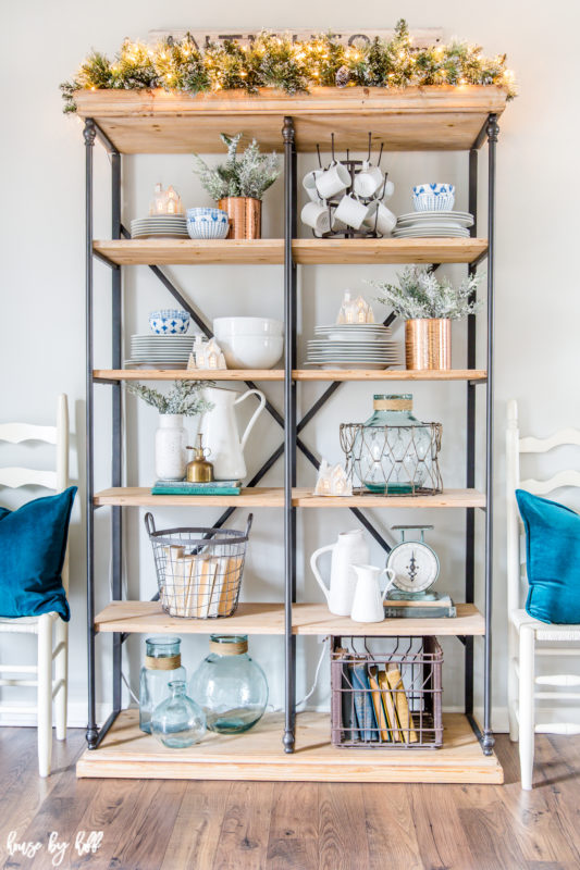 Open shelving unit with steel and wood, every shelf filled with cups, plates and glass.