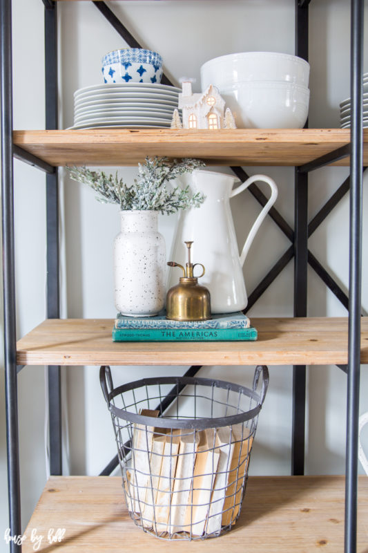 White vase filled with greenery on the middle shelf.