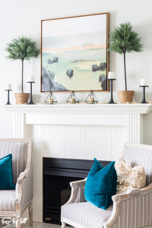 Teal throw pillows are on the armchairs by the fireplace.