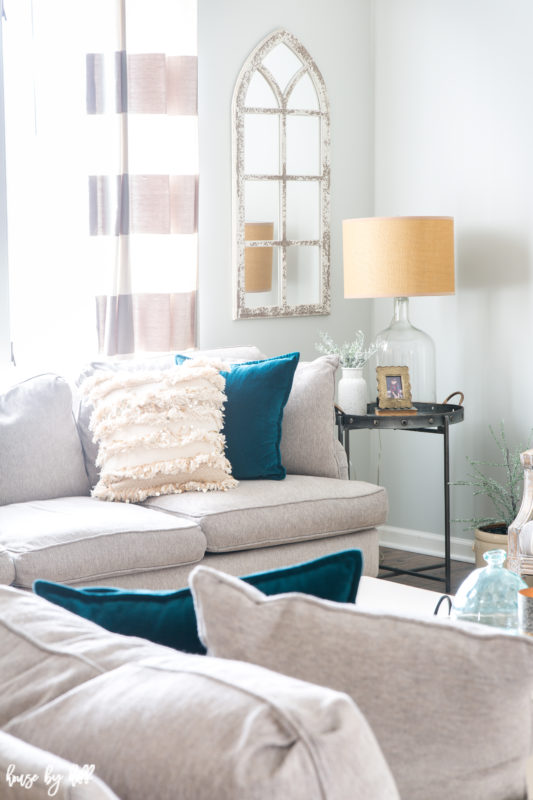 White sectional couches are in the living room with teal pillows.