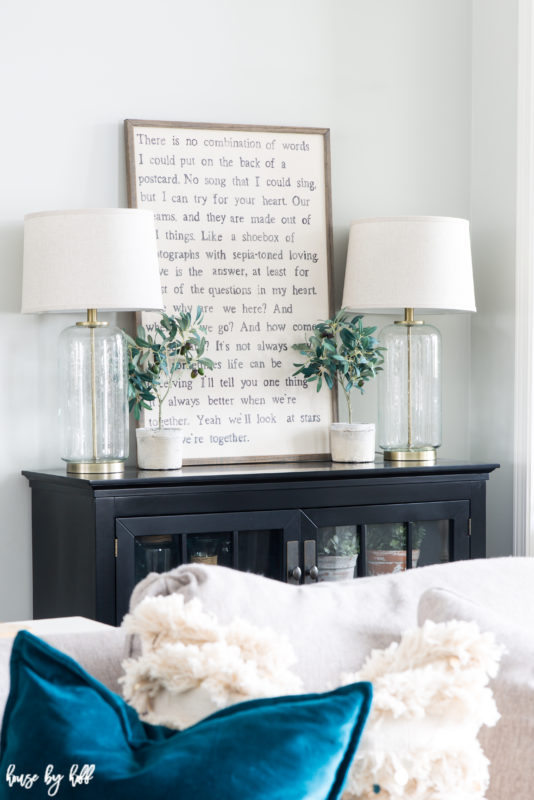 A sideboard in the living room with a framed graphic quote on it.