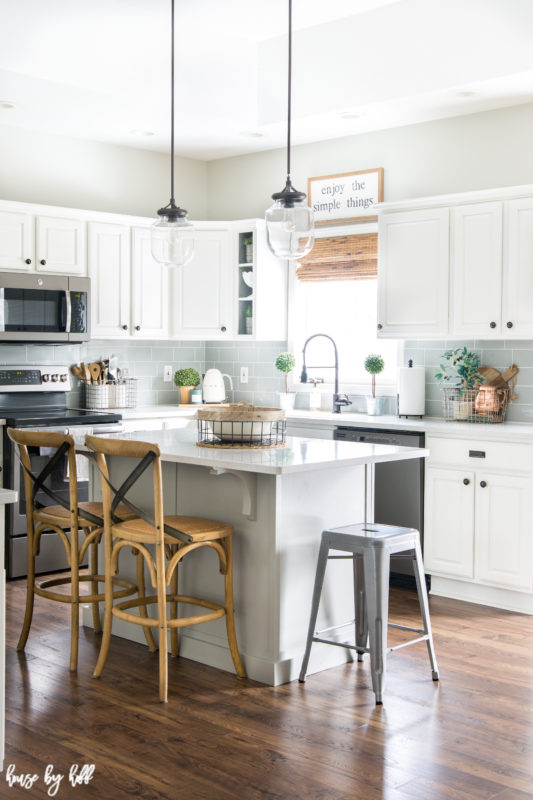 A white kitchen island with wooden chairs and a small stool.