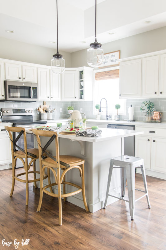 A neutral white kitchen with brown chairs at the island.