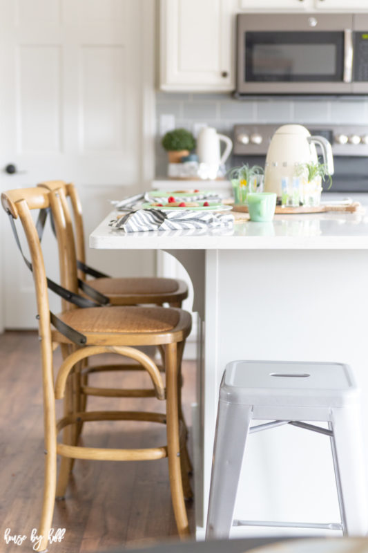 A white kitchen island with wooden chairs around it.