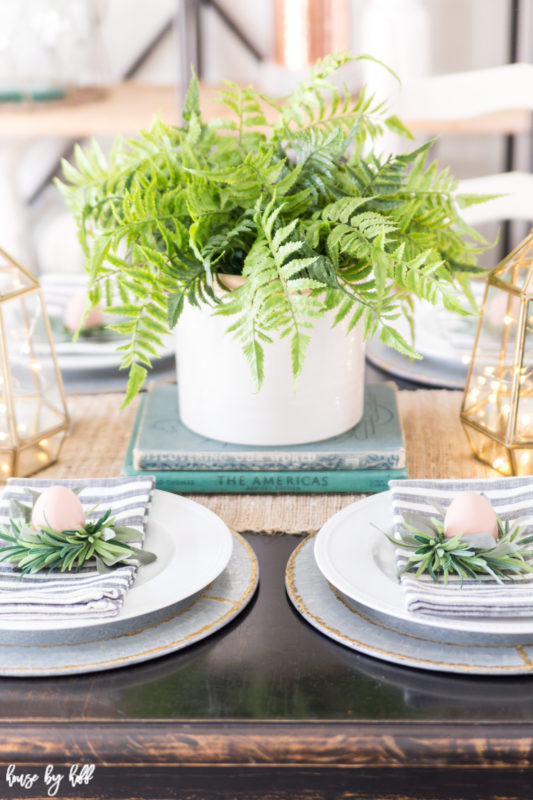 The potted fern is on old books as a centerpiece on the table.