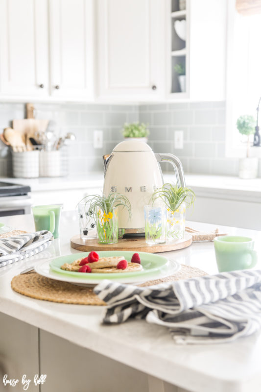 A Smeg kettle is beside a plate of waffles.