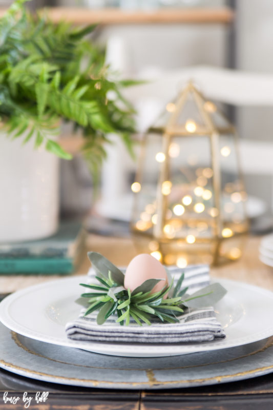 A little faux egg is on the napkin on the plates on the table.