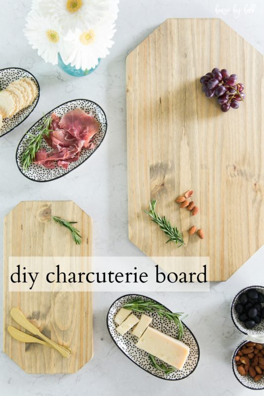 A small and a large DIY charcuterie board with grapes on the larger one and gold knives on the smaller one.